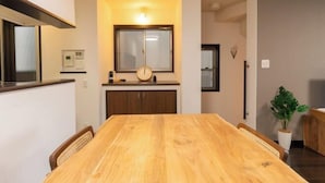 A dining area with a wooden table, chairs, a clock, and a small potted plant. - 10 Min Walk to Ikebukuro Station 4BR Private House 3 Min to Kanamecho Sleeps 8 (Tokyo)