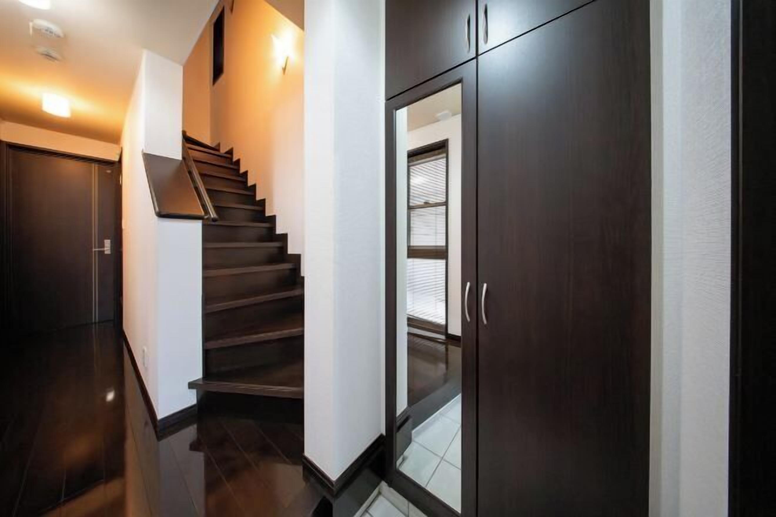 A modern interior with a dark wooden staircase, a glass door with a window, and a light-colored wall.