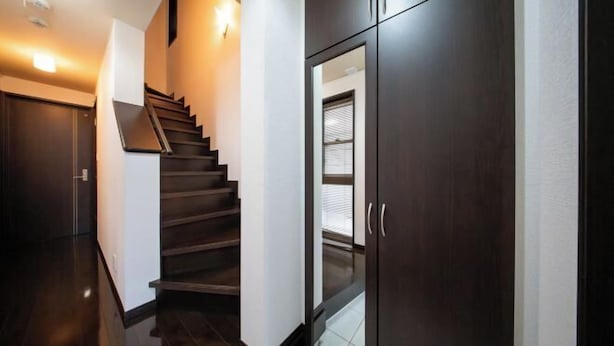 A modern interior with a dark wooden staircase, a glass door with a window, and a light-colored wall. - 10 Min Walk to Ikebukuro Station 4BR Private House 3 Min to Kanamecho Sleeps 8 (Tokyo)