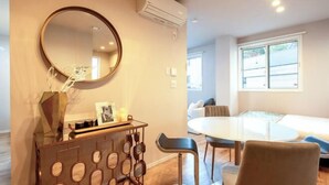 A modern living room with a round mirror, a wooden console table, a round dining table, and two chairs. - Ciel MinamiAzabu (Tokyo)