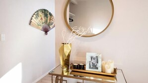A room with a round mirror, a decorative fan, a glass table with a gold vase, candles, and a framed photo. - Ciel MinamiAzabu (Tokyo)