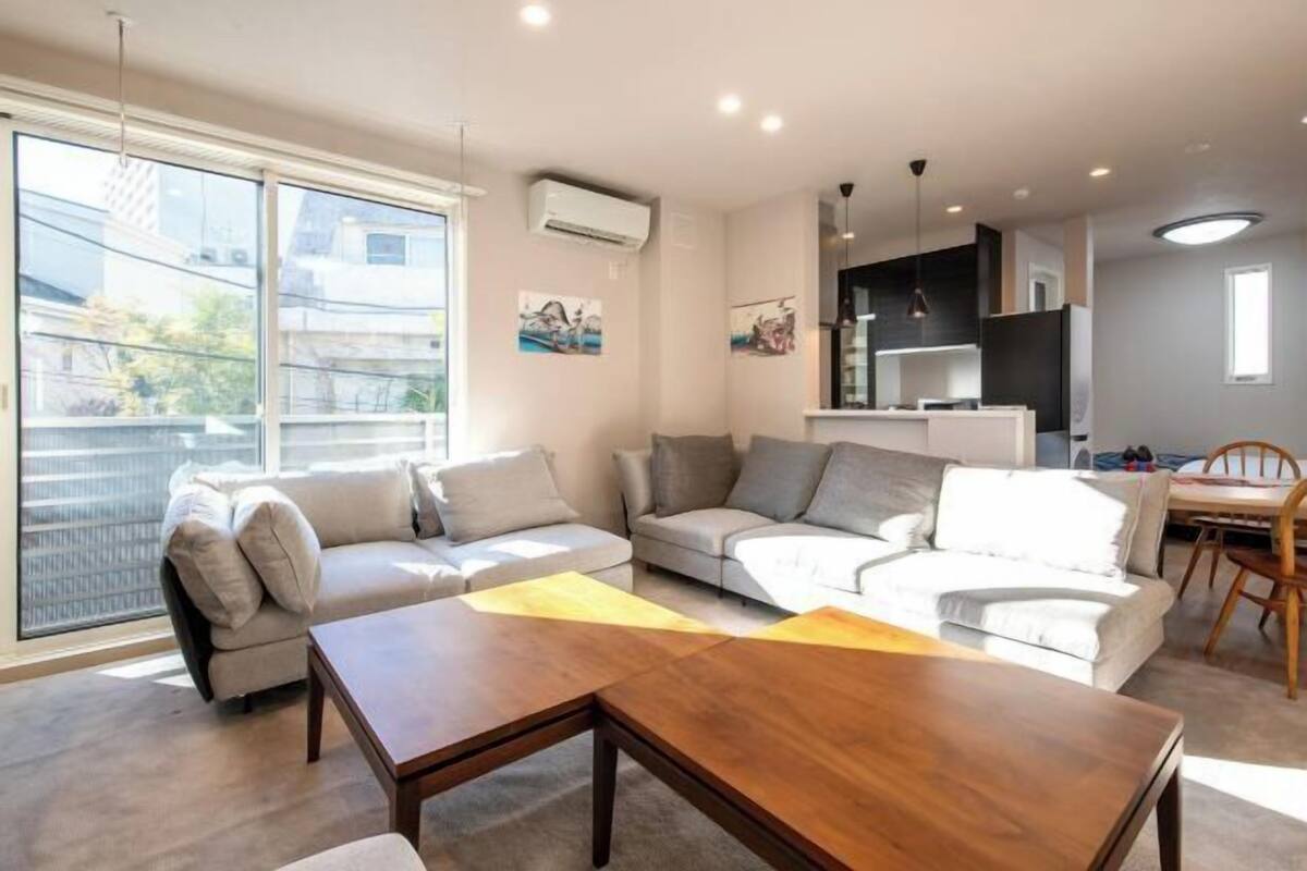 A modern living room with a sofa set, a wooden coffee table, and a dining area with a chair and table.