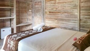 A room with a bed, a small white appliance, and wooden paneling. - Coconut Village Guest House Lembongan RedPartner (Bali)