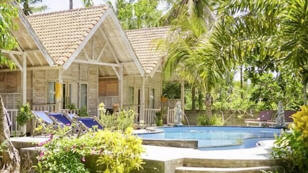 A pool area with lounge chairs, a small pool, and wooden structures with tiled roofs. - Coconut Village Guest House Lembongan RedPartner (Bali)
