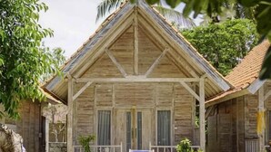 A wooden building with a triangular roof, two blue lounge chairs, and a small porch area. - Coconut Village Guest House Lembongan RedPartner (Bali)