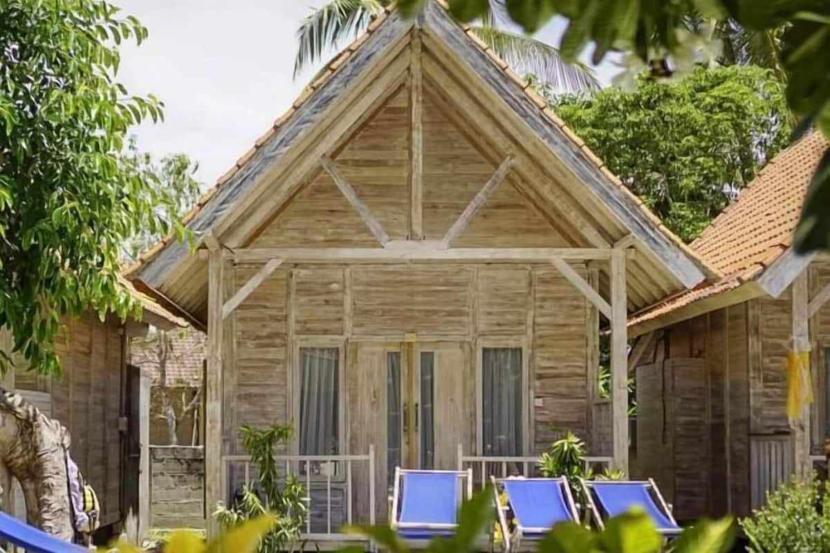 A wooden building with a triangular roof, two blue lounge chairs, and a small porch area.