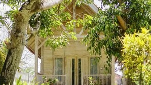 A wooden house with a porch, surrounded by greenery. - Coconut Village Guest House Lembongan RedPartner (Bali)