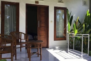 Una habitación con puerta de madera, una mesa pequeña y sillas. Hay una planta a la derecha.
