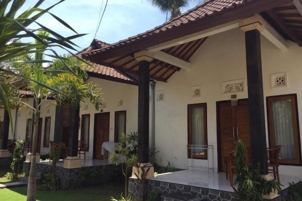 A building with a tiled roof, multiple doors, and a stone-paved courtyard.