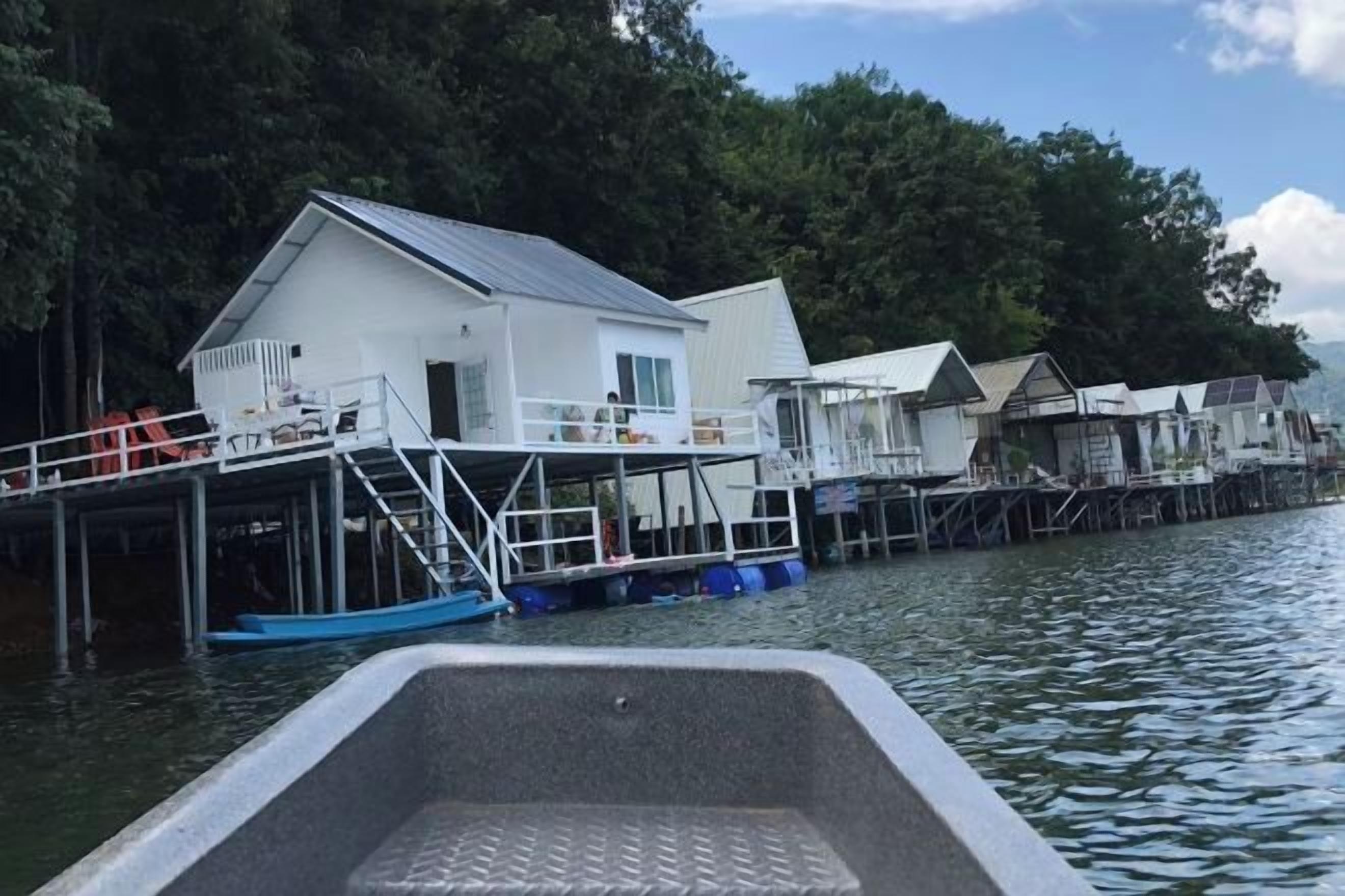 A waterfront property with multiple docked boats, a white building with a balcony, and a dock extending into the water.