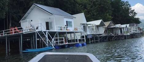 A waterfront property with multiple docked boats, a white building with a balcony, and a dock extending into the water.