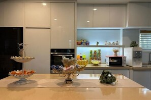A modern kitchen with white cabinets, a two-tiered serving tray, a microwave, and various kitchen appliances.