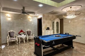 A pool table in a room with marble flooring, two armchairs, a small table with a vase, and a chandelier. - Melodies Castle Homestay (Johor Bahru)