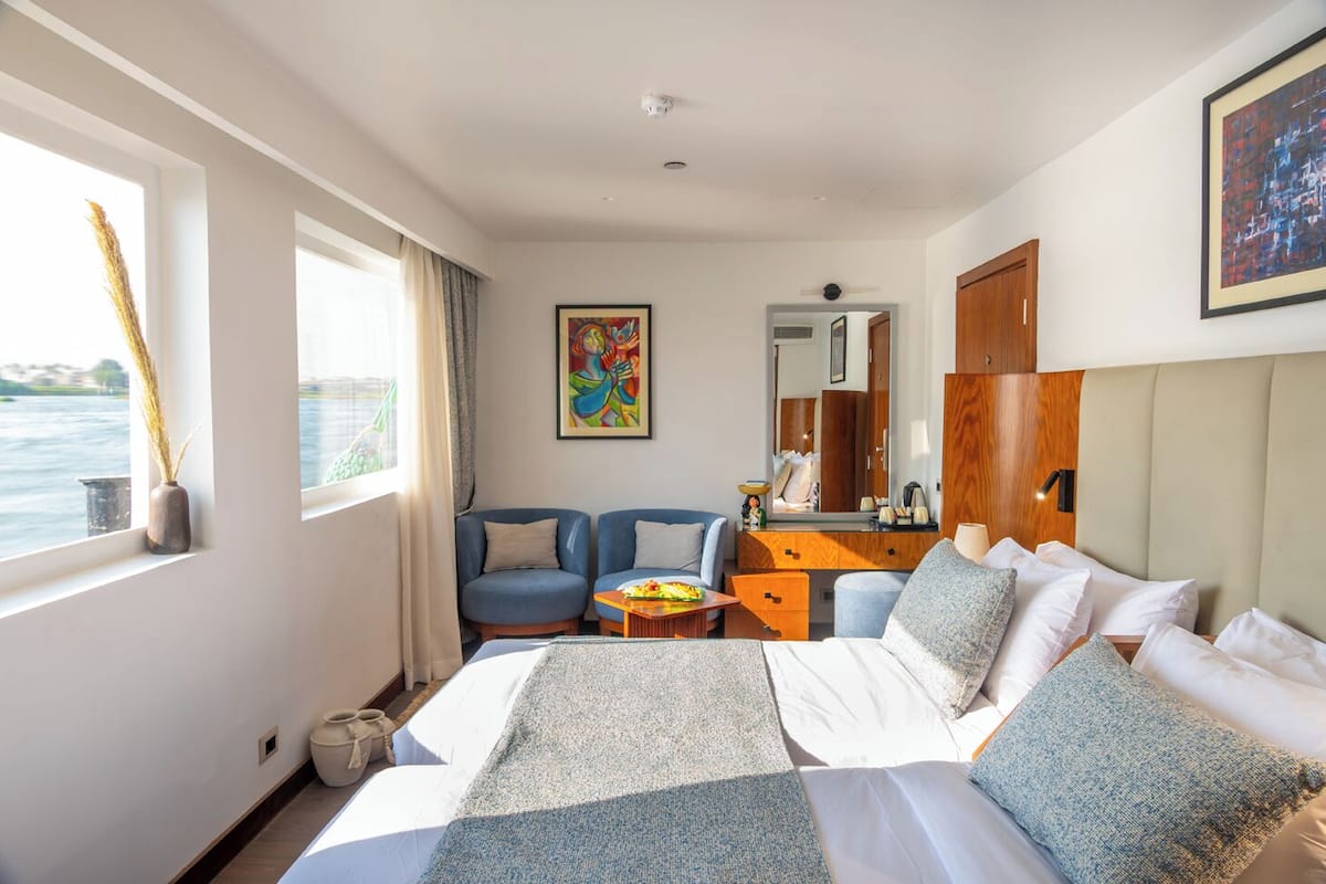 A hotel room with a bed, a desk, a chair, and a view of the water.
