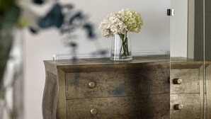 A wooden dresser with a vase of white flowers on top.