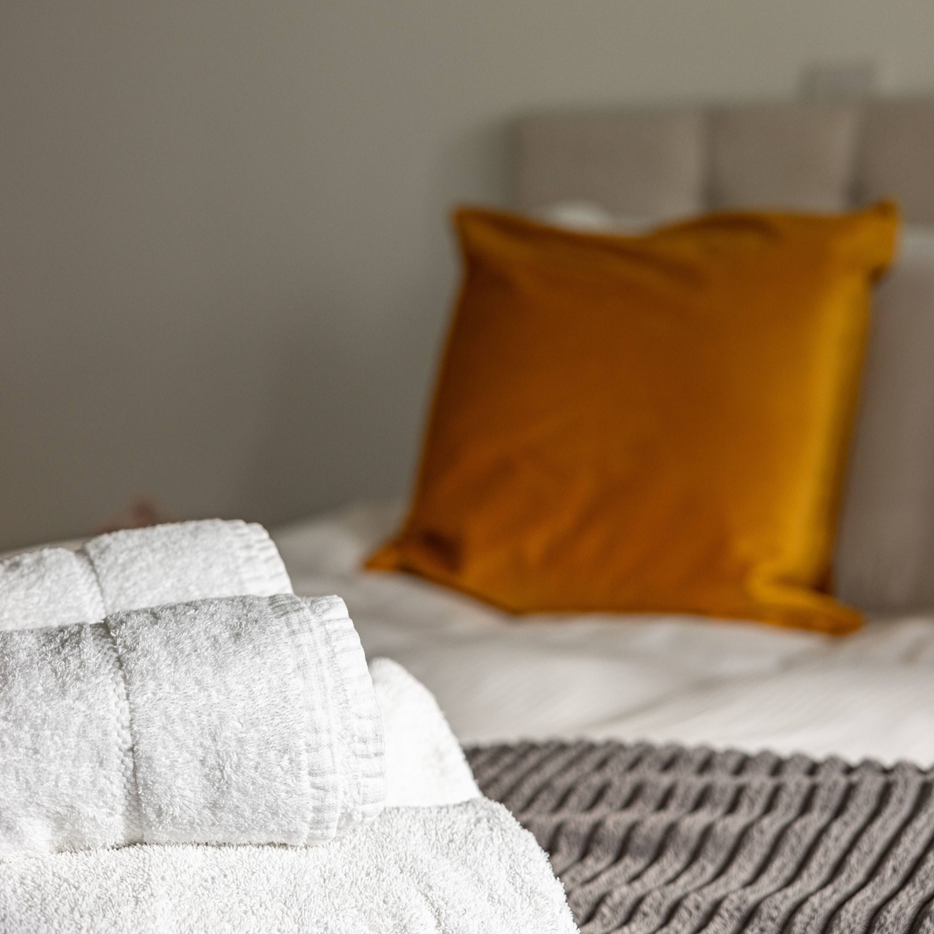 Ein Bett mit weißer Decke und einer grauen, strukturierten Tagesdecke.