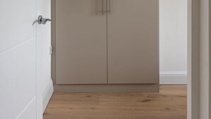 Ein geschlossener Kleiderschrank mit Griff, eine weiße Wand und ein Holzboden.