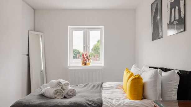 Ein Schlafzimmer mit Bett, Fenster, Heizkörper und Tür.