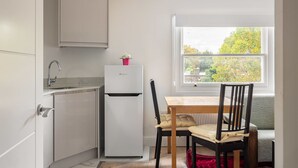 Eine kleine Küche mit Kühlschrank, Spüle und Fenster mit Blick auf Bäume.