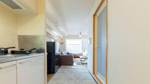 A narrow corridor leading to a kitchenette with a stove, refrigerator, and cabinets. - 2 stops to Shinjuku, 7 minutes to train station, for families and couples, close to Tokyo City Hall (Tokyo)