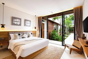 A modern bedroom with a large bed, a desk, and a view of a tropical garden through a sliding glass door. - Villa Ubud Escape by BaliSuperHost (Bali)