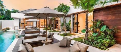 A modern outdoor living area with a pool, lounge seating, and a wooden wall.