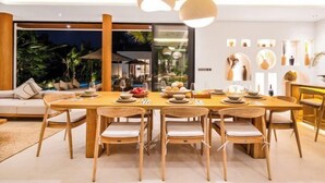A modern dining area with a wooden table set for a meal, surrounded by wooden chairs. - Villa Ubud Escape by BaliSuperHost (Bali)