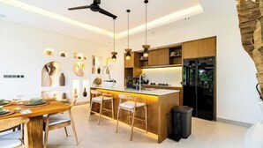 A modern kitchen with a central island, pendant lighting, and wooden cabinetry. - Villa Ubud Escape by BaliSuperHost (Bali)