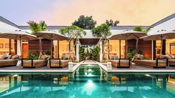 A poolside area with lounge chairs and umbrellas, a clear pool, and a modern building in the background. - Villa Ubud Escape by BaliSuperHost (Bali)