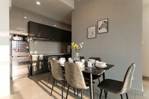 A modern kitchen with a dining table set for four, featuring a vase of flowers and a refrigerator.