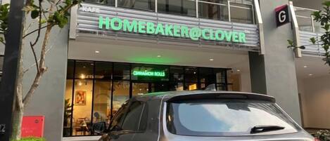 A storefront with a sign reading 'HOMEBAKER@CLOVER' and a car parked in front.