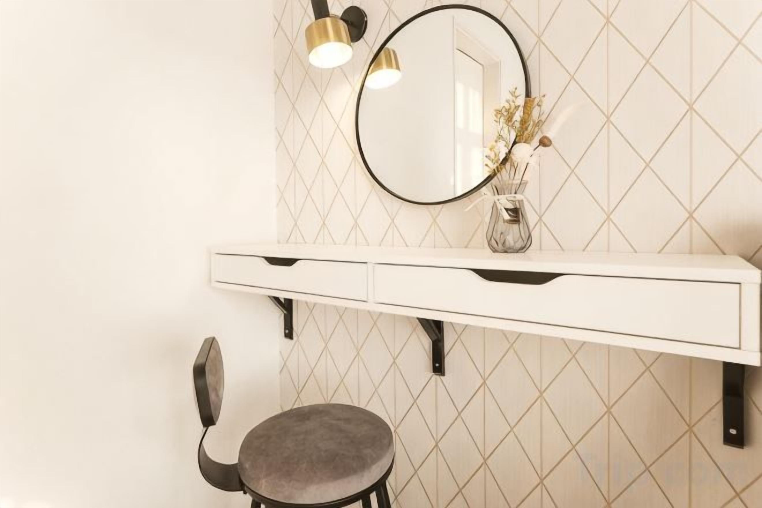A bathroom vanity with a mirror, a vase with flowers, and a chair.