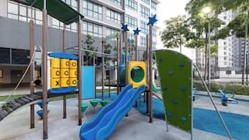 A playground with slides and climbing structures, surrounded by a building with large windows.
