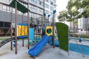 Un parque infantil con toboganes y estructuras para escalar, rodeado por un edificio con grandes ventanales.