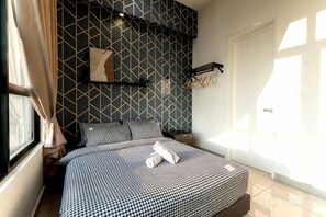 Une chambre à coucher avec un mur à motifs, un lit recouvert d’une courtepointe à carreaux et une fenêtre avec des rideaux.
