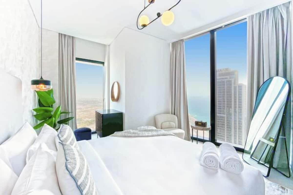 A modern hotel room with a large bed, a view of the city, and a balcony.