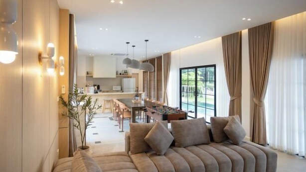 A modern living room with a sofa, dining area, and kitchen in the background. - Tierra en Sierra (Pak Chong)