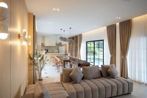 A modern living room with a sofa, dining area, and kitchen in the background.