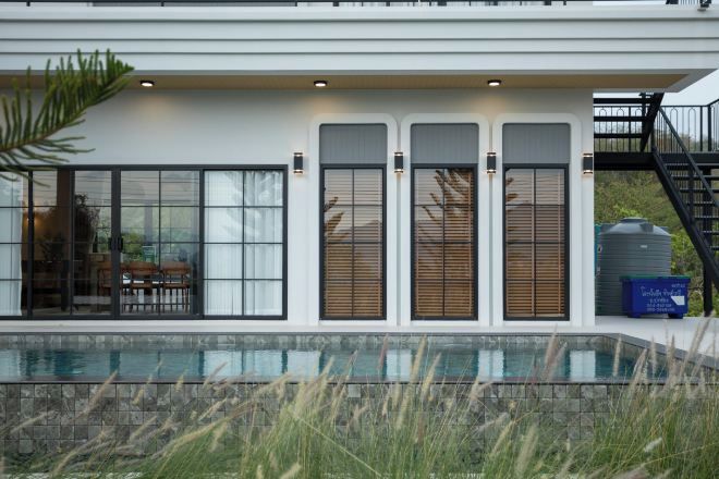 Una casa moderna con un amplio ventanal, una piscina y una escalera.