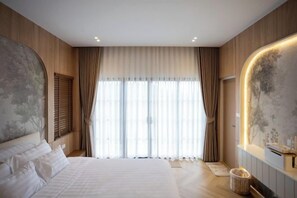 A modern bedroom with a large bed, a wall-mounted TV, and a window with curtains. - Tierra en Sierra (Pak Chong)