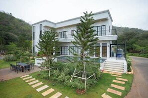 A modern two-story house with a patio, outdoor seating, and a well-maintained lawn. - Tierra en Sierra (Pak Chong)
