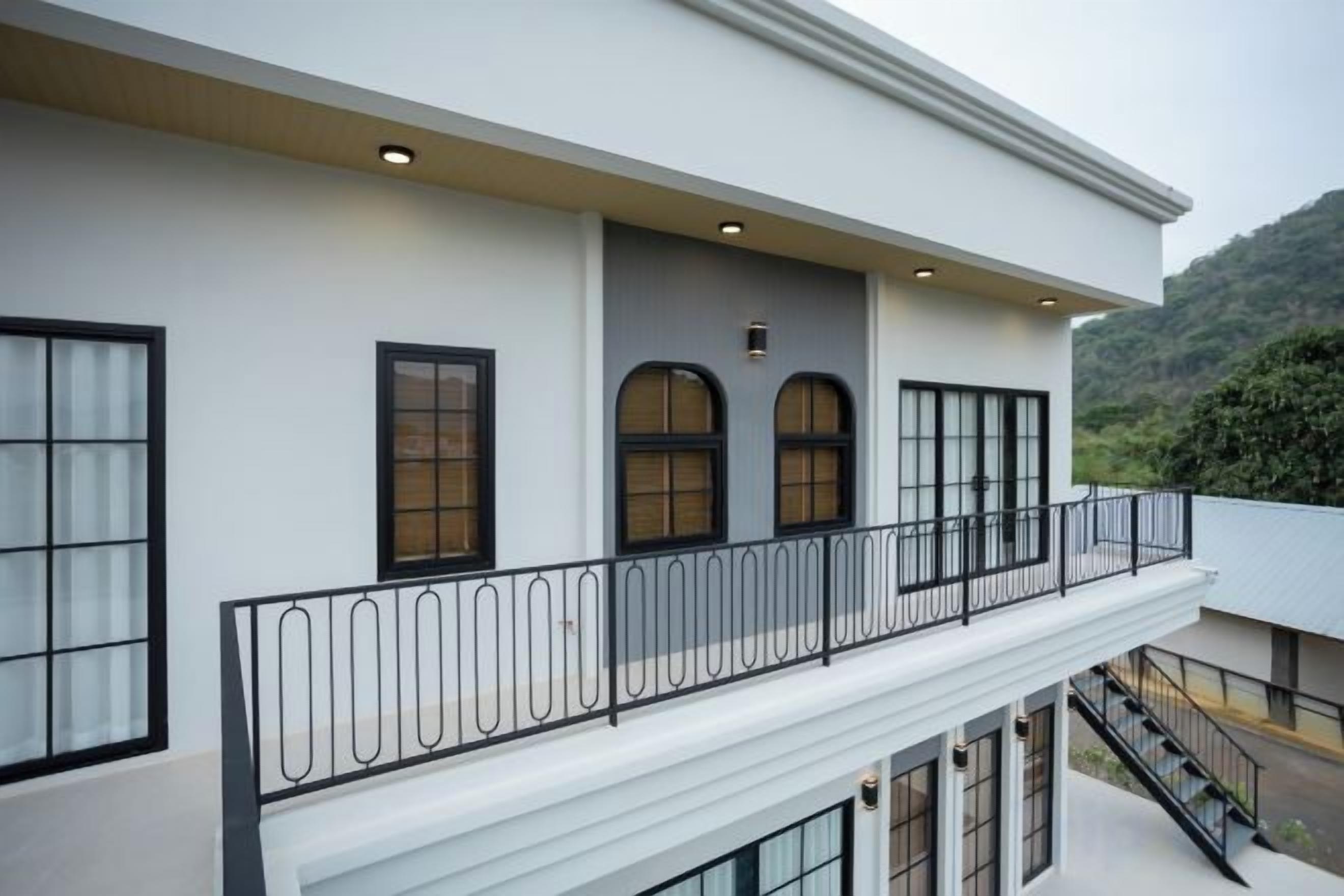 A modern building with a balcony, large windows, and a staircase.