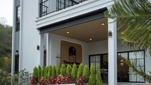A modern two-story building with a balcony, a wooden sign, and a well-maintained garden. - Tierra en Sierra (Pak Chong)