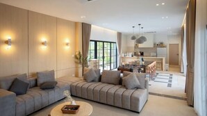 A modern living room with a sofa, a coffee table, and a kitchen in the background. - Tierra en Sierra (Pak Chong)