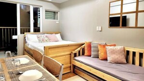 Een kleine kamer met een bed, een tafeltje en een raam.
