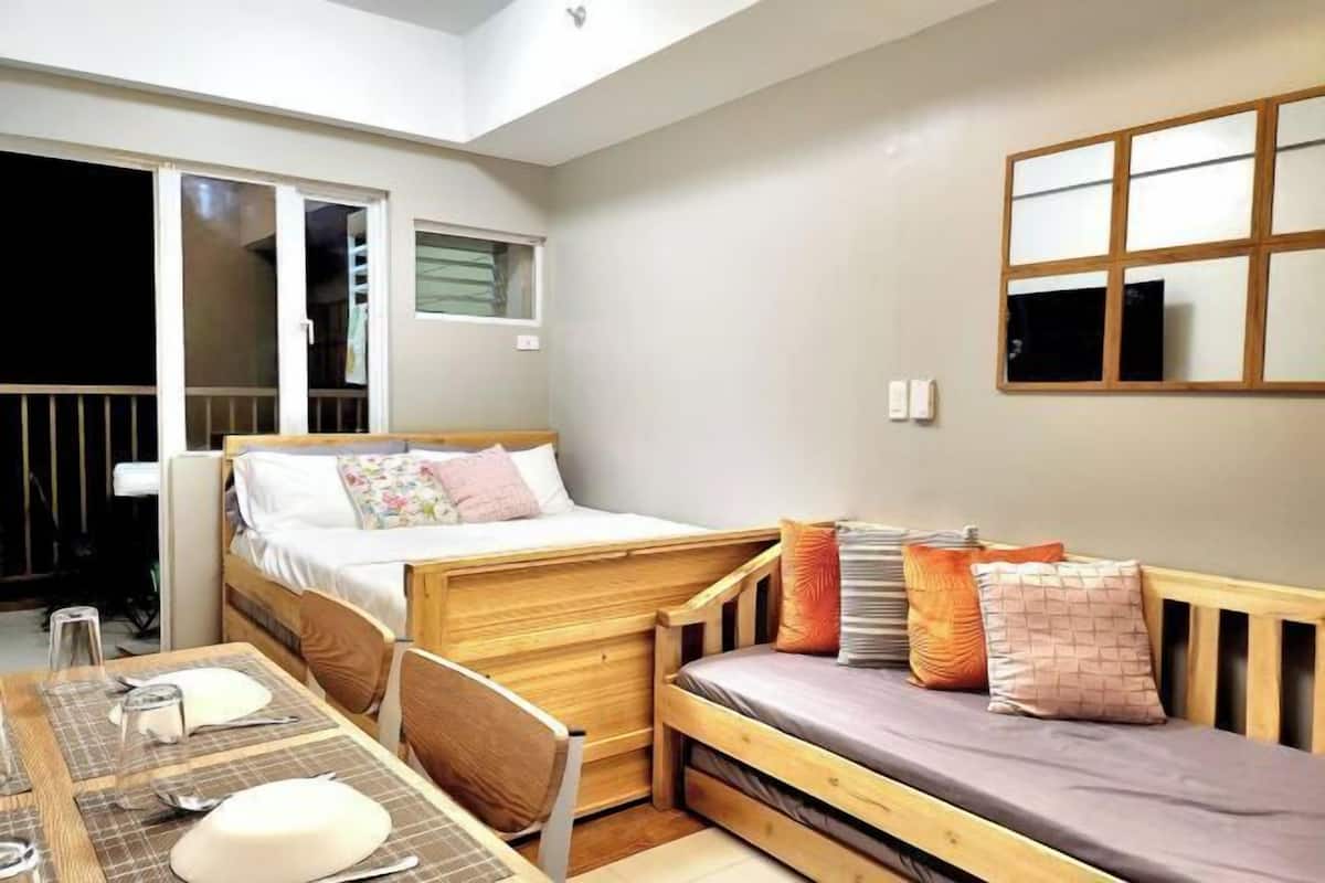 Une petite chambre comprenant un lit, une petite table et une fenêtre.