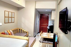 Ein kleines Hotelzimmer mit zwei Betten, einem Esstisch und einem Fernseher.