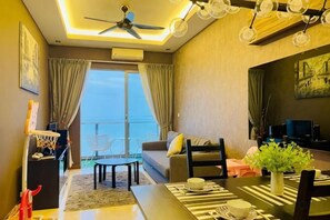 Un salon moderne doté d’un ventilateur de plafond, d’une table à manger avec des chaises, d’un canapé et offrant une vue sur l’extérieur grâce à de grandes fenêtres.