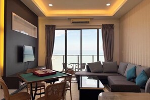 Une chambre d’hôtel avec vue sur la piscine, un canapé, une table à manger et un téléviseur à écran plat.