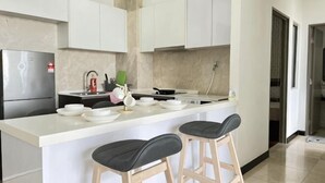 Een moderne keuken met een centraal eiland, barstoelen, een koelkast en een spoelbak.